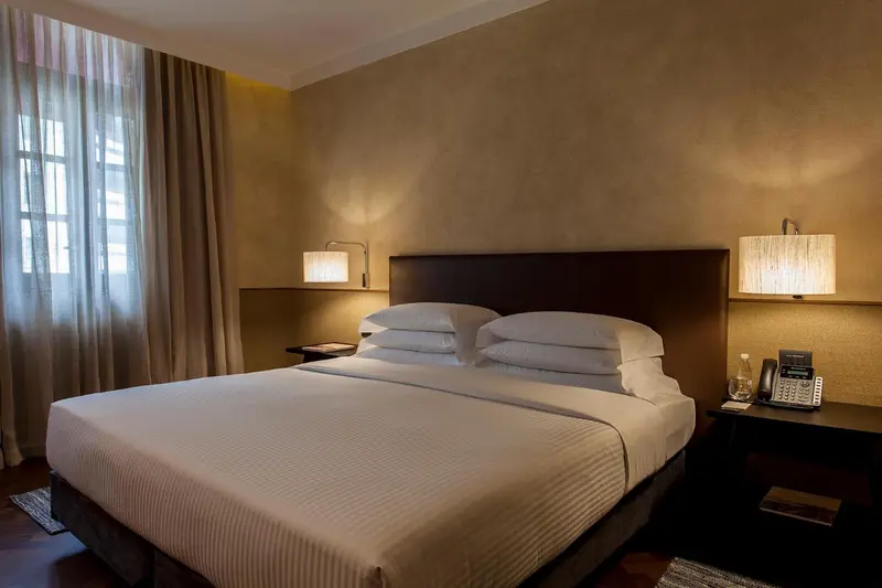 Une chambre avec un grand lit recouvert de draps blancs et deux lampes de chevet.