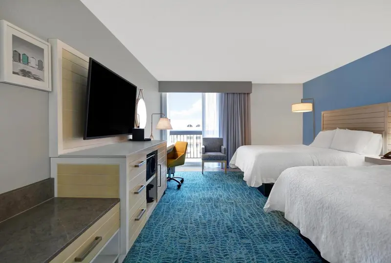 Chambre d'hôtel lumineuse avec deux lits et vue sur l'océan.
