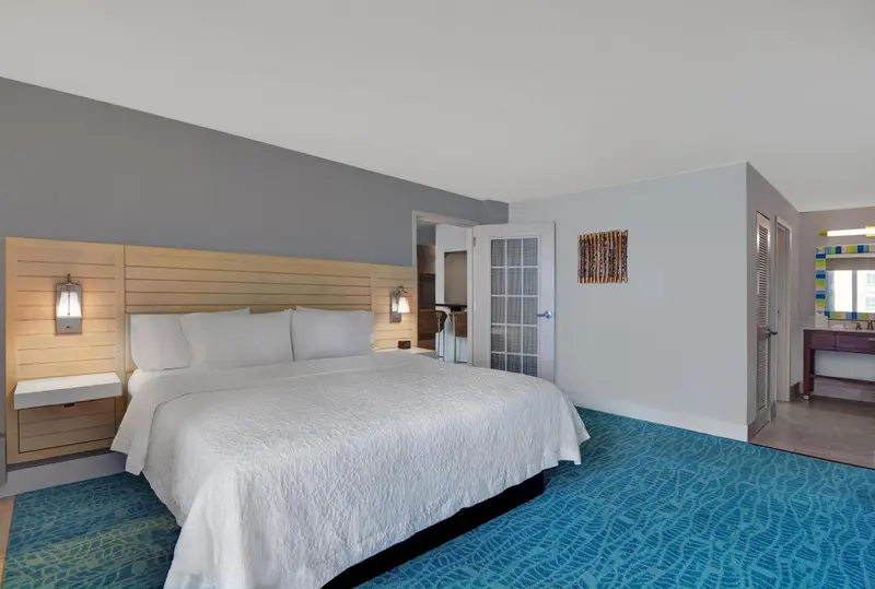 Une chambre lumineuse avec un grand lit recouvert d'une couette blanche.