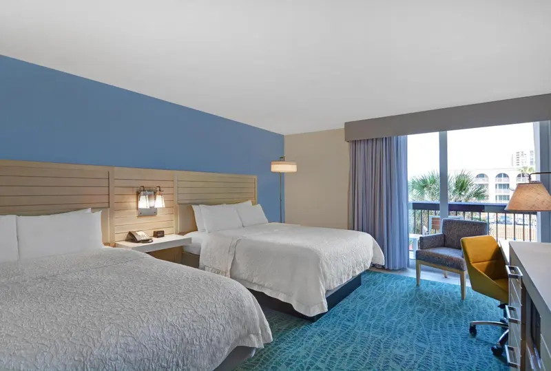 Chambre lumineuse avec deux lits et vue sur la mer.