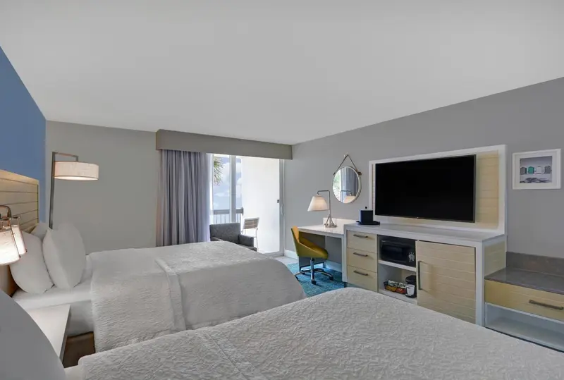 Une chambre d'hôtel lumineuse avec deux lits et un bureau.
