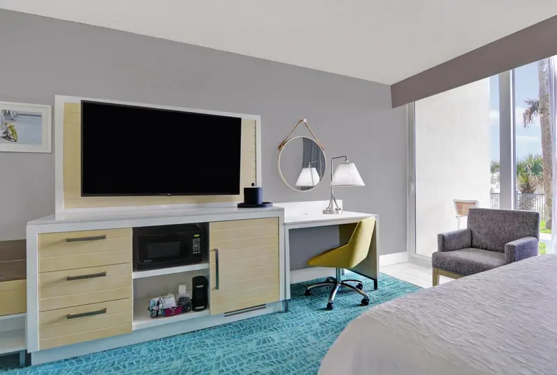 Une chambre d'hôtel lumineuse avec un grand téléviseur et un bureau.