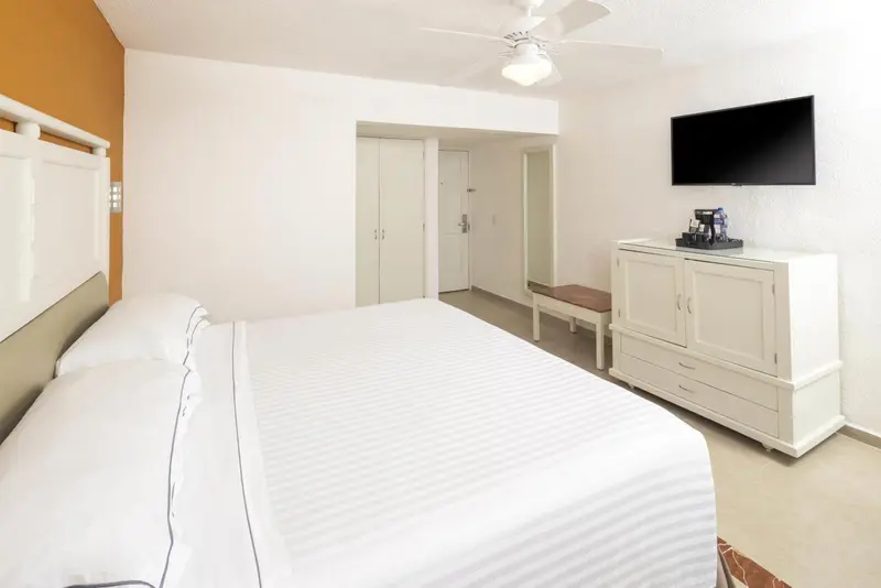 Une chambre lumineuse avec un grand lit et un meuble de télévision.
