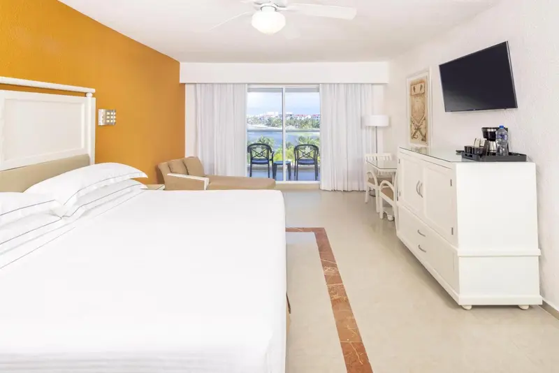 Chambre lumineuse avec un grand lit et une vue sur la mer.