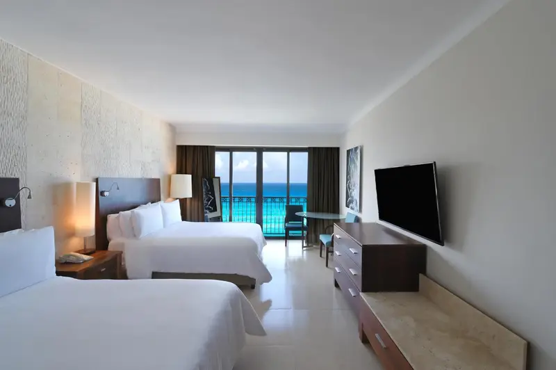 Chambre lumineuse avec lits jumeaux et vue sur la mer.