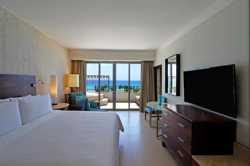 Chambre lumineuse avec un grand lit et vue sur la mer.