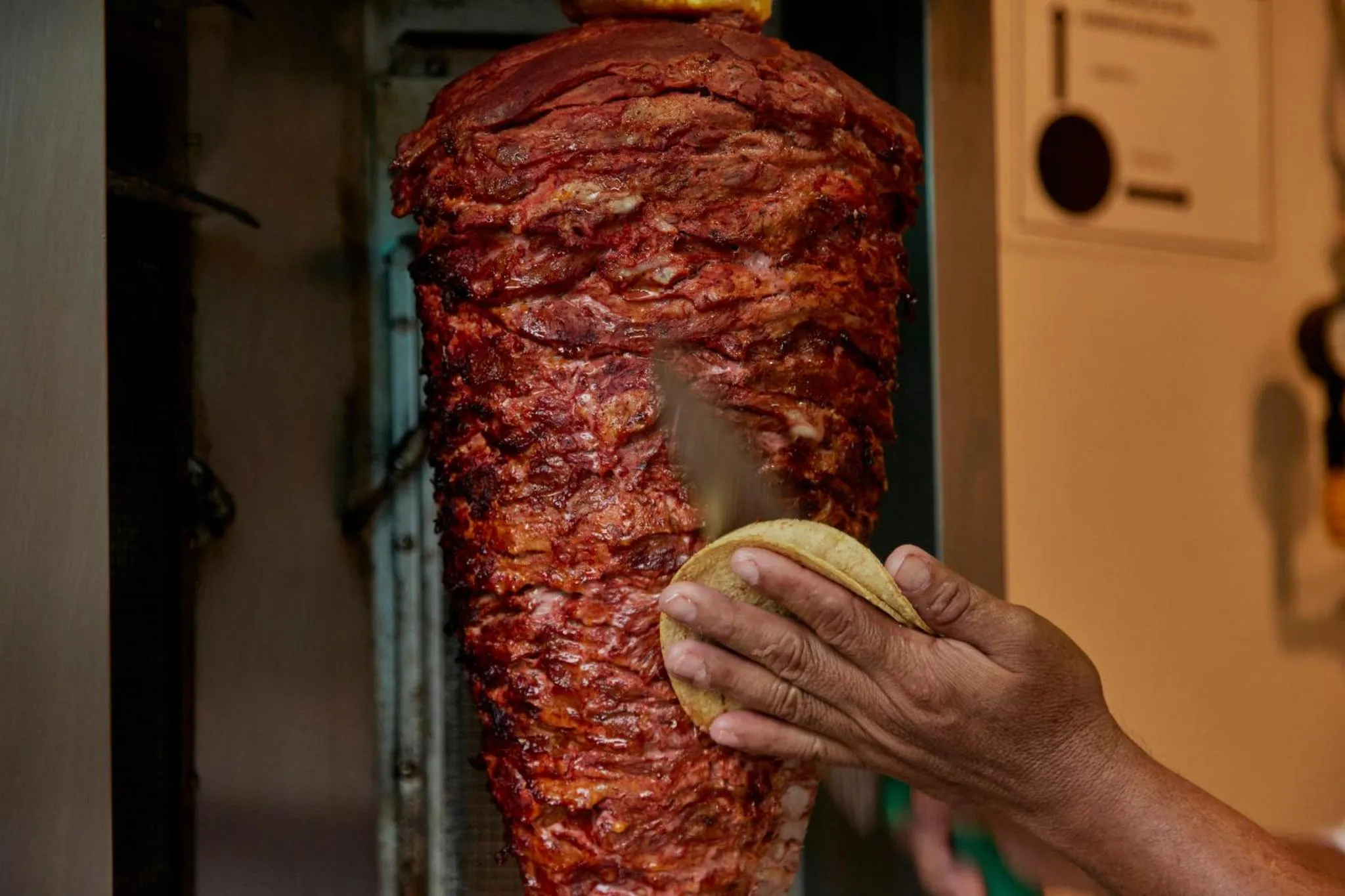 Viande grillée à la broche avec une main préparant un pain.