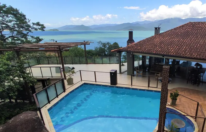 Une piscine bleue avec une terrasse en bois et une vue sur la mer et les montagnes.