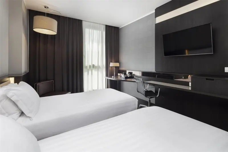 Chambre moderne avec deux lits simples et un bureau.