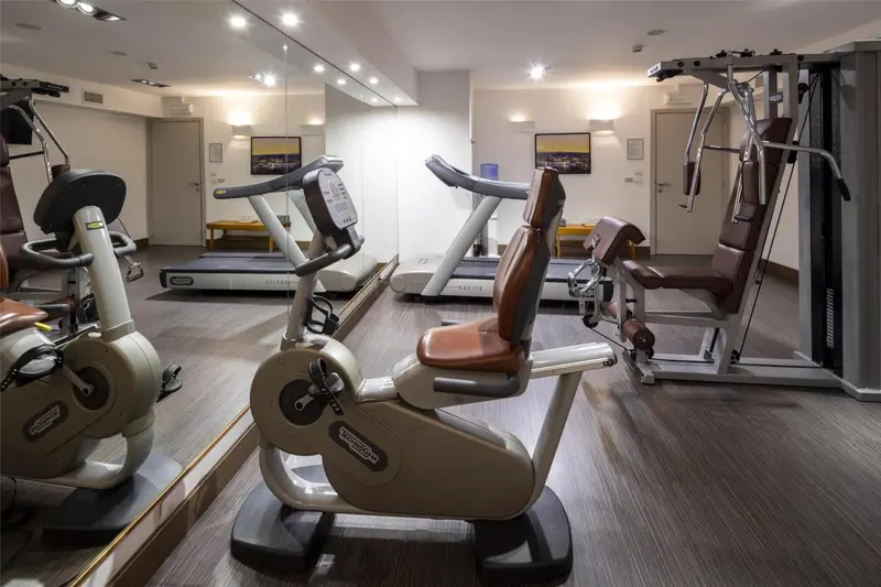 Une salle de sport lumineuse avec plusieurs appareils de musculation et des miroirs.
