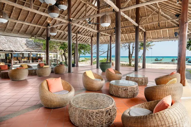 Espace de détente extérieur avec mobilier en rotin et vue sur la mer.