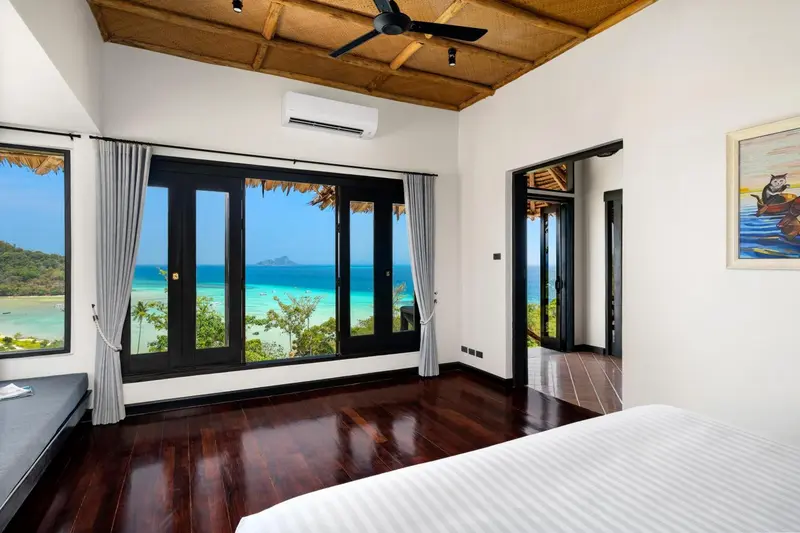 Une chambre lumineuse avec vue sur la mer à travers de grandes baies vitrées.