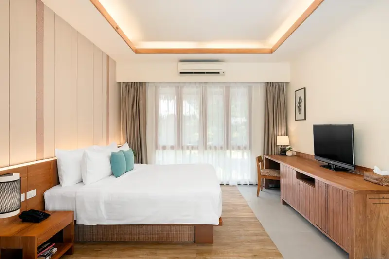 Une chambre lumineuse avec un grand lit et un bureau en bois.