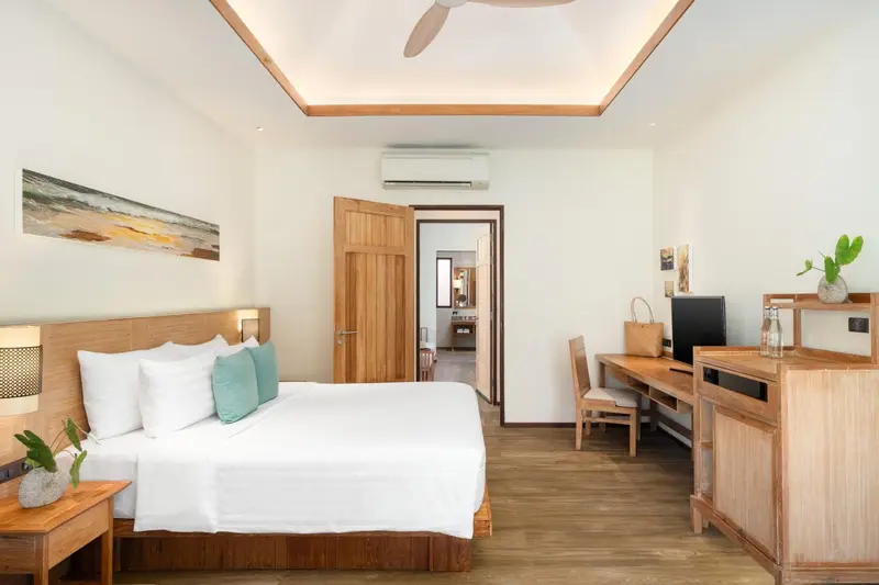 Une chambre lumineuse avec un grand lit et un bureau en bois.