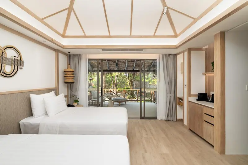 Chambre lumineuse avec un lit double et une terrasse ombragée.