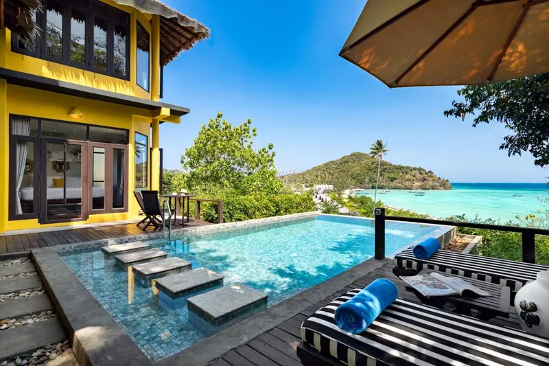 Une piscine à débordement offre une vue sur la mer turquoise et la végétation luxuriante.