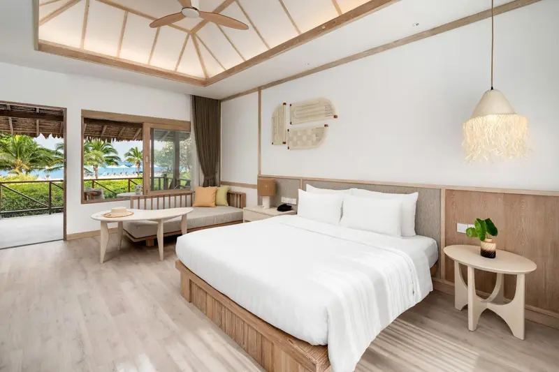 Une chambre lumineuse avec un grand lit et un coin salon.