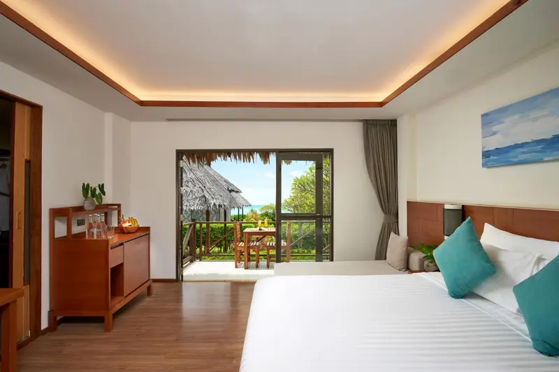 Chambre lumineuse avec un lit confortable et une vue sur la végétation tropicale.