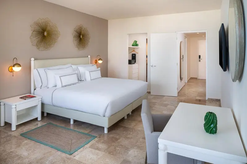 Chambre lumineuse avec un grand lit blanc et une décoration murale.