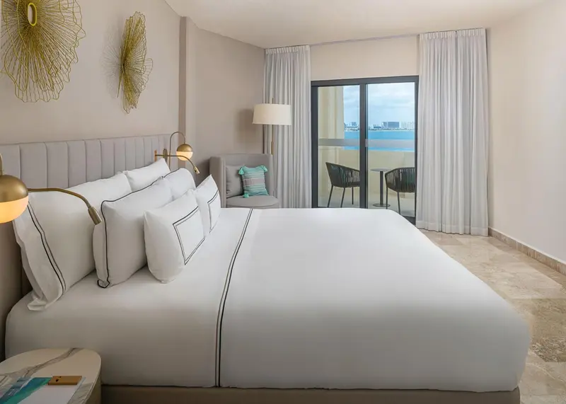 Une chambre lumineuse avec un grand lit et un accès à un balcon.