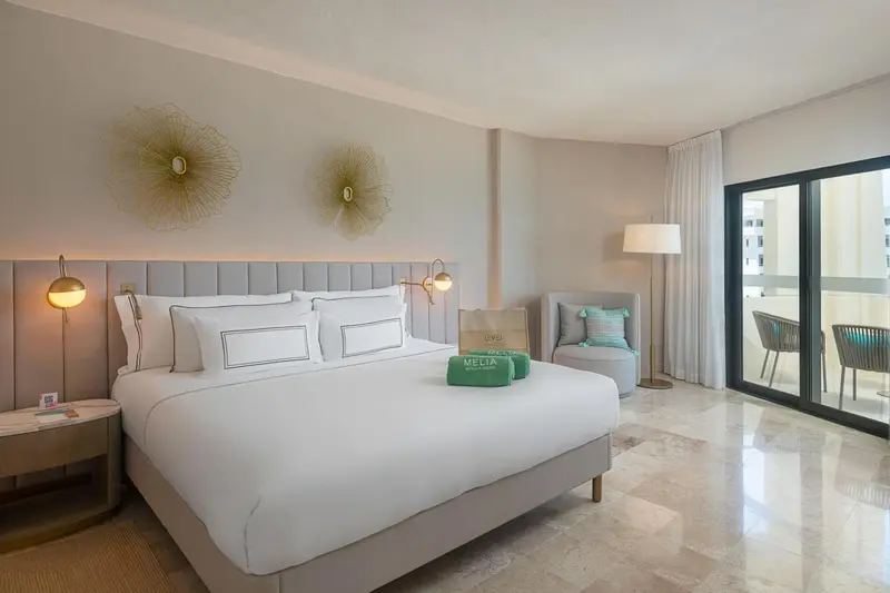 Une chambre lumineuse avec un grand lit et un fauteuil.