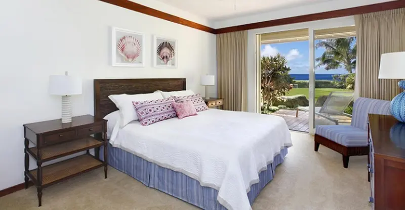 Une chambre lumineuse avec un grand lit et vue sur un jardin tropical.