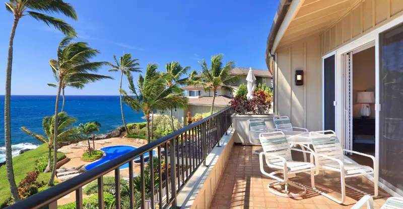 Terrasse avec mobilier d'extérieur donnant sur la mer et la végétation.
