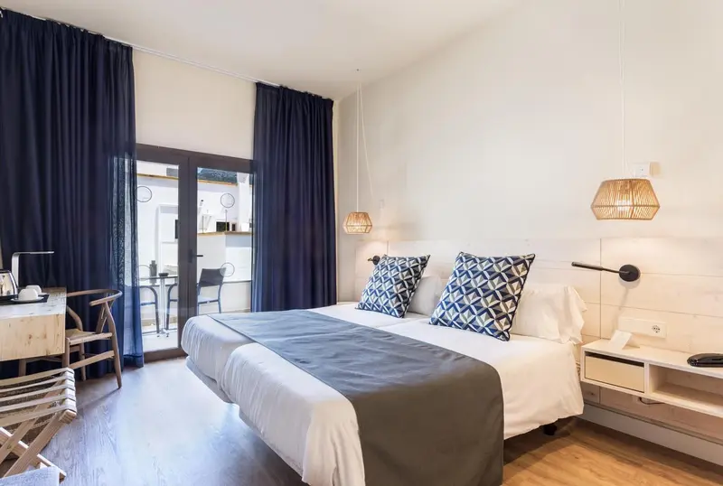 Une chambre lumineuse avec un lit double et un bureau.