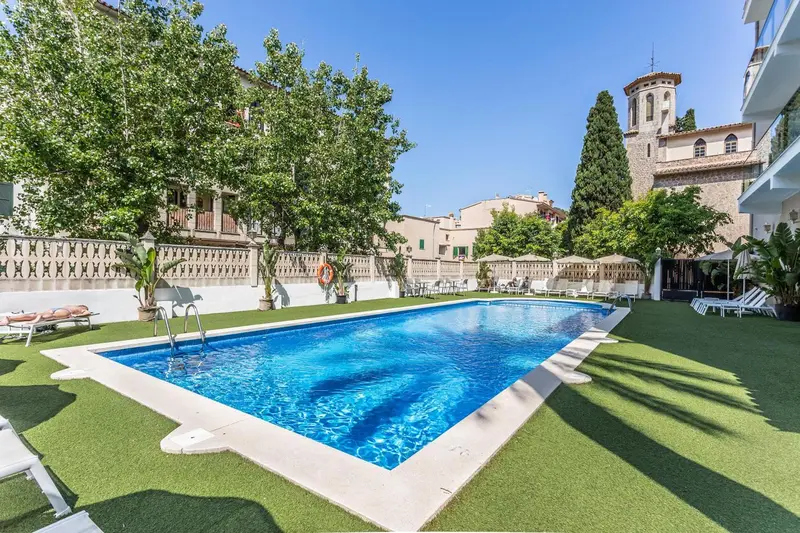 Une piscine rectangulaire entourée d'une pelouse verte et de bâtiments.
