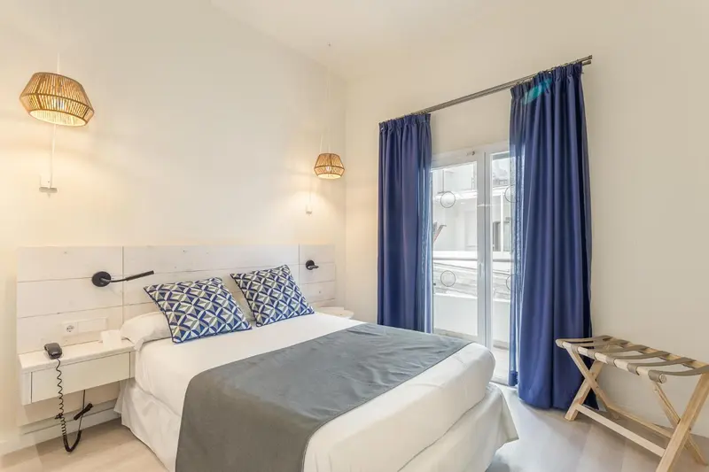 Une chambre lumineuse avec un lit double et un accès à une terrasse.