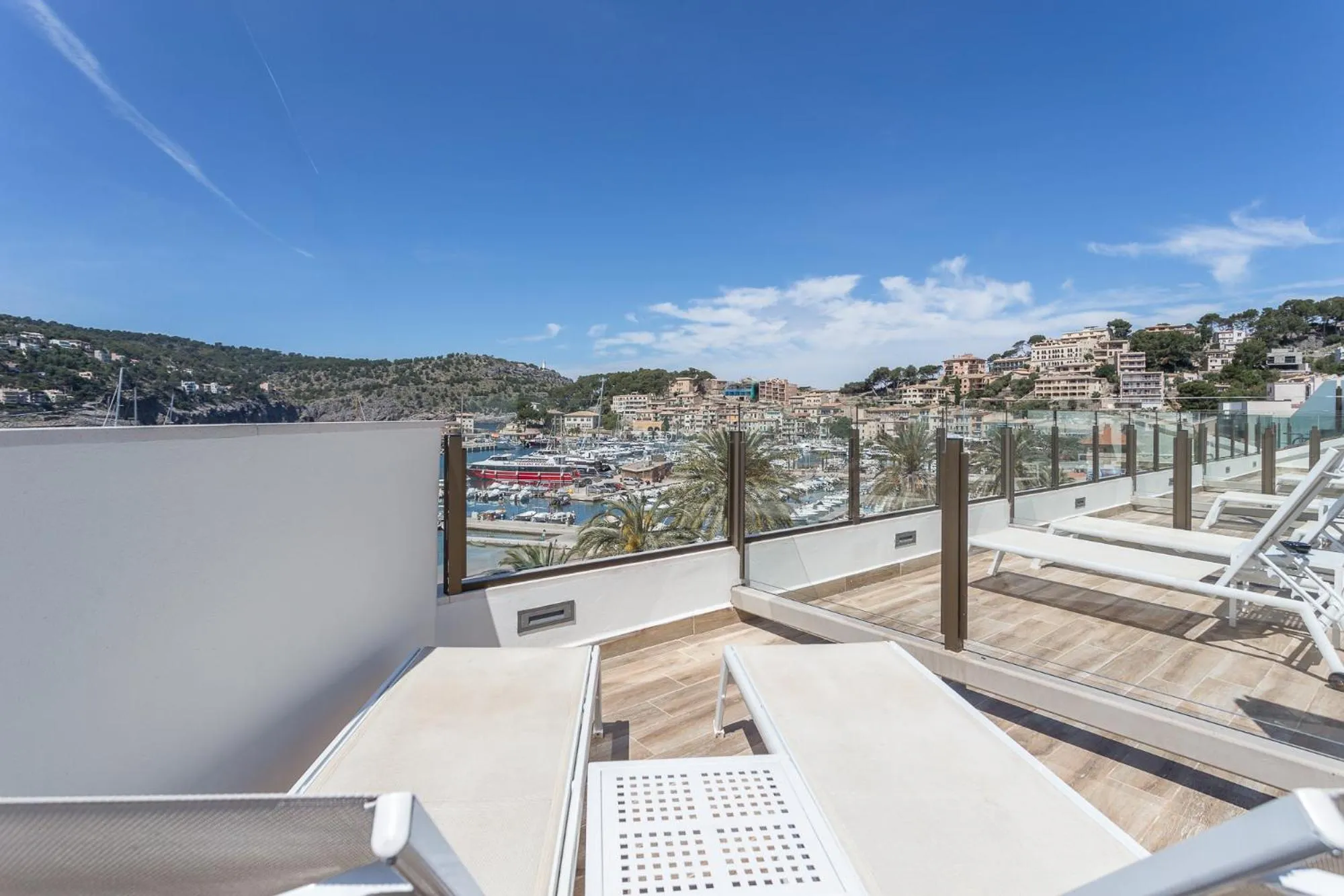 Terrasse avec transats et vue sur la mer et la ville.