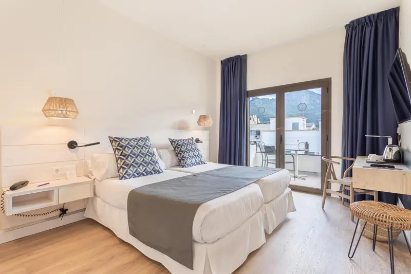 Chambre lumineuse avec un lit double et un accès à une terrasse.