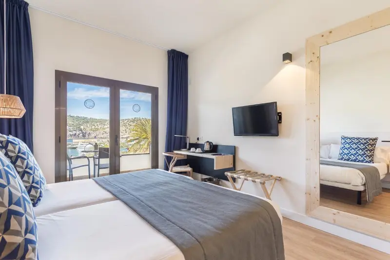 Une chambre lumineuse avec un lit double et un bureau donnant sur une vue sur la mer.
