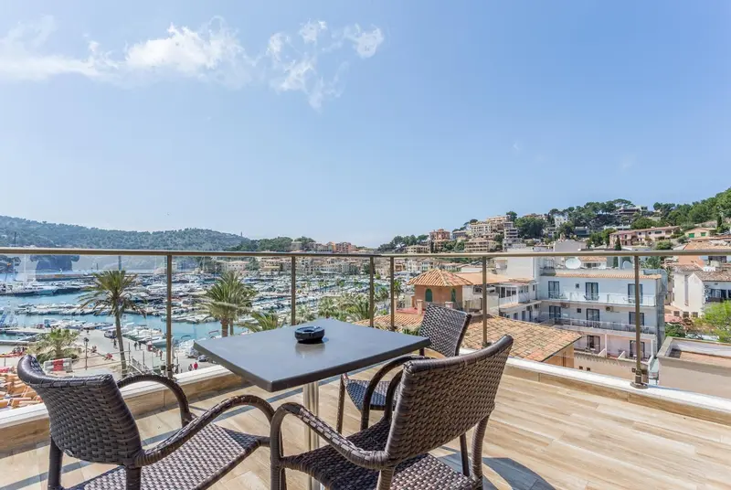 Une terrasse avec une table et des chaises offre une vue sur un port de plaisance et la ville.