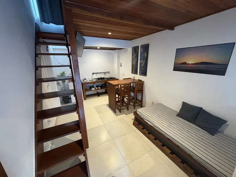 Une piece de sejour avec un canape, une cuisine et un escalier menant a une mezzanine.