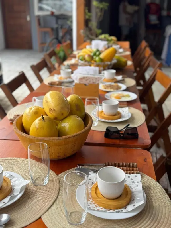 Une table est dressée avec des fruits et des couverts pour le petit-déjeuner.