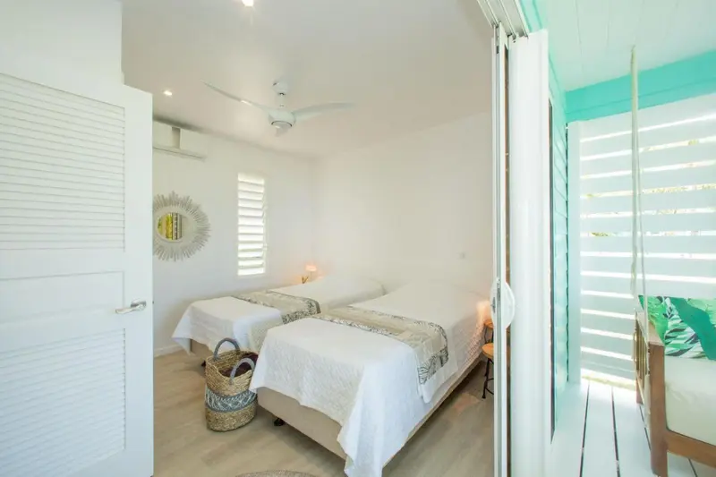 Chambre lumineuse avec deux lits simples et décoration murale.