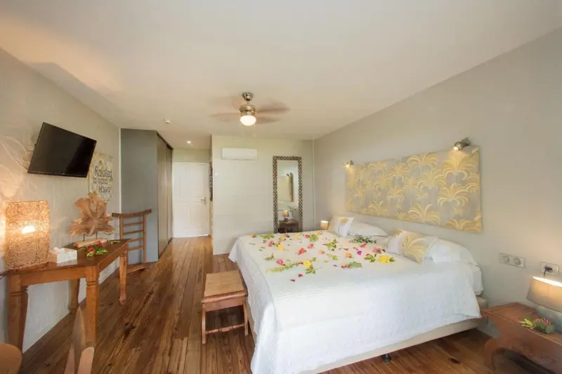 Une chambre lumineuse avec un lit décoré de fleurs et un téléviseur mural.