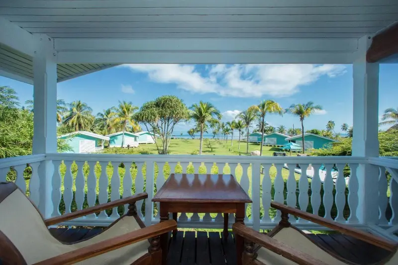 Terrasse avec mobilier en bois donnant sur une végétation tropicale et la mer.