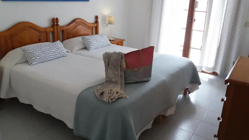 Une chambre lumineuse avec un lit double et une commode en bois.