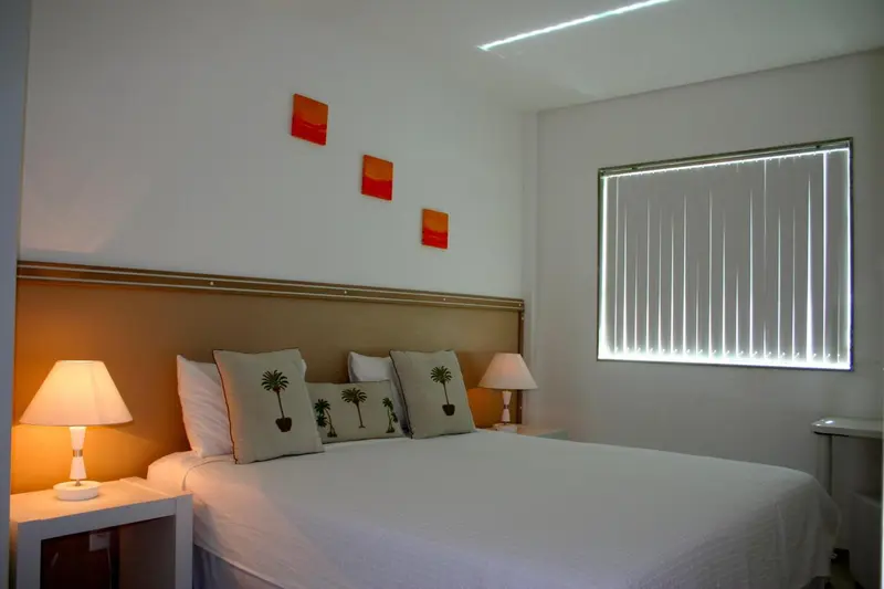 Une chambre lumineuse avec un grand lit recouvert de coussins.
