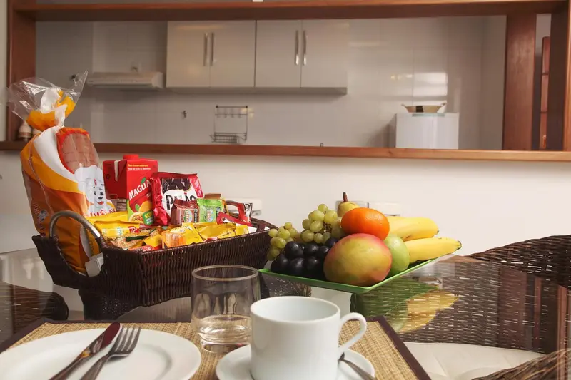 Une table est dressée avec un panier de fruits et des viennoiseries.
