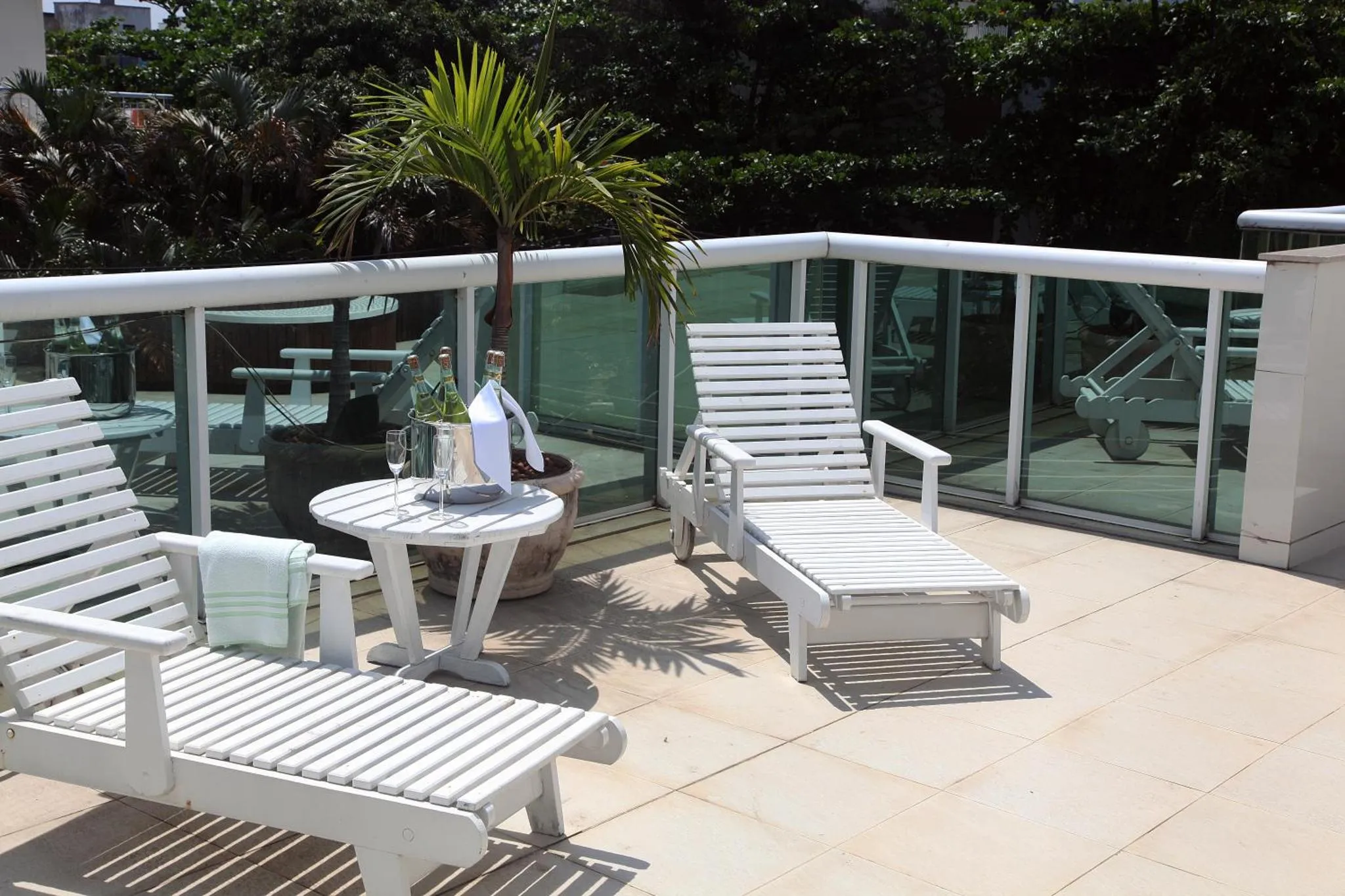 Terrasse ensoleillée avec transats et table basse.