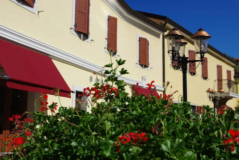 Façade d'un bâtiment jaune avec des volets bruns et un auvent rouge.