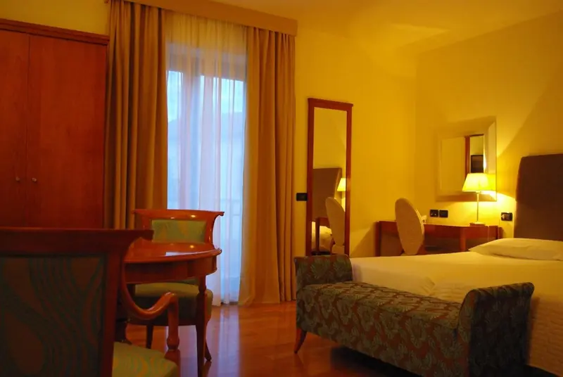 Une chambre lumineuse avec un lit, des fauteuils et un bureau.