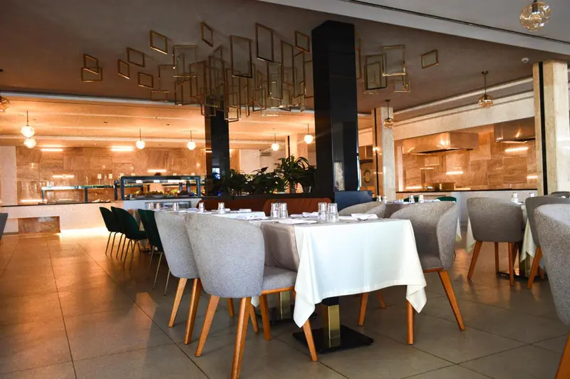 Une salle lumineuse avec des tables dressées pour un repas.