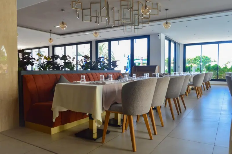 Une salle lumineuse avec des tables dressées et des banquettes confortables.