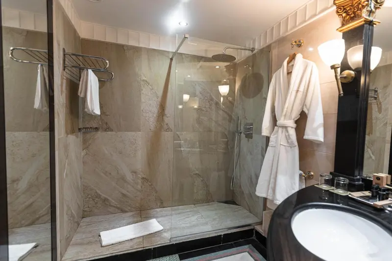 Une salle de bain moderne avec une douche à l'italienne et des peignoirs blancs.