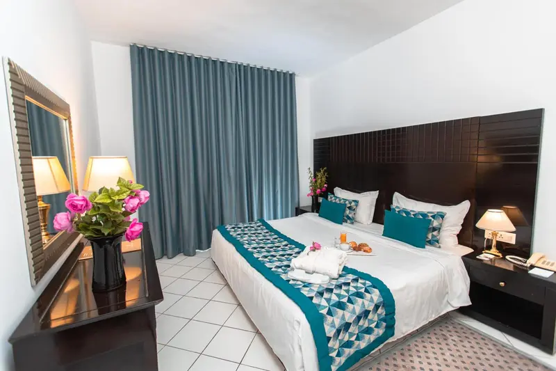 Une chambre lumineuse avec un grand lit et des fleurs fraîches.