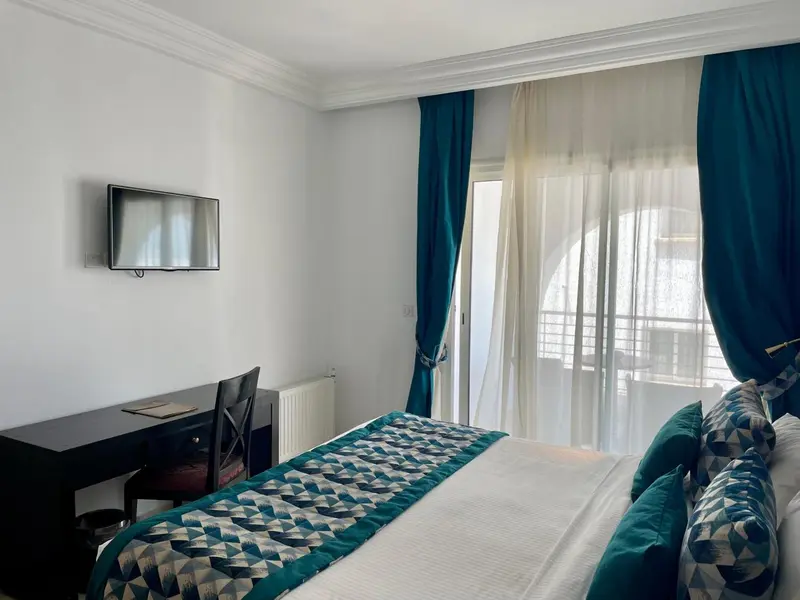 Une chambre avec un lit et un bureau près d'une fenêtre.